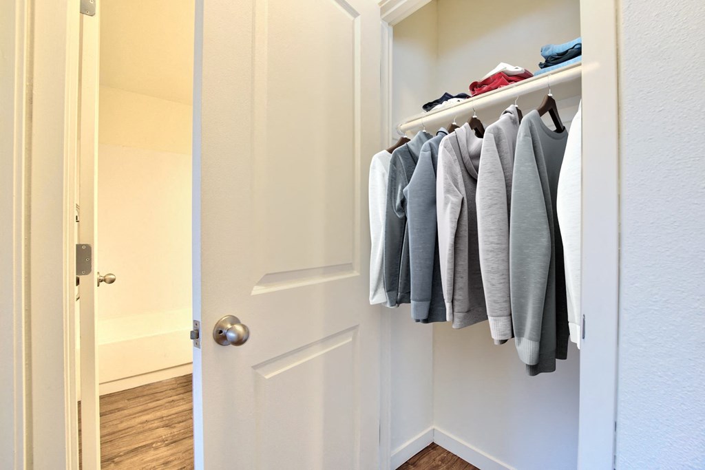 a walk in closet with clothes hanging on a rack