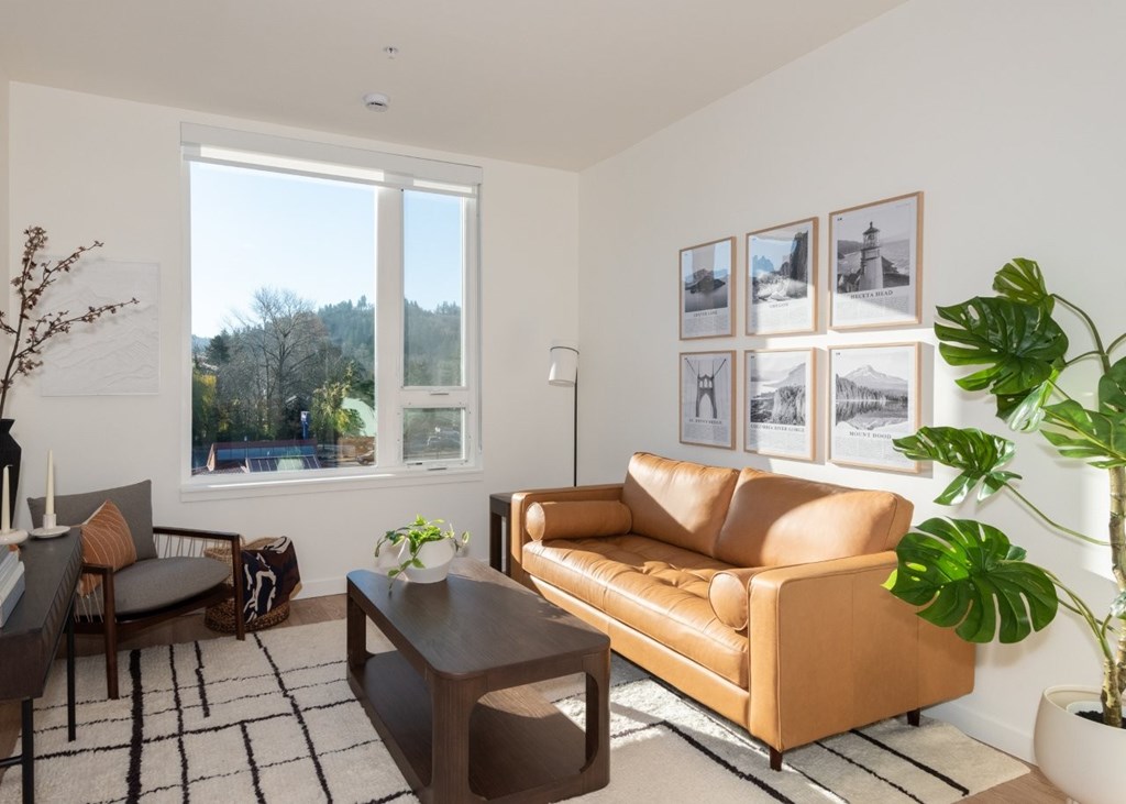 A living room with a tan couch, a coffee table, and a large window.