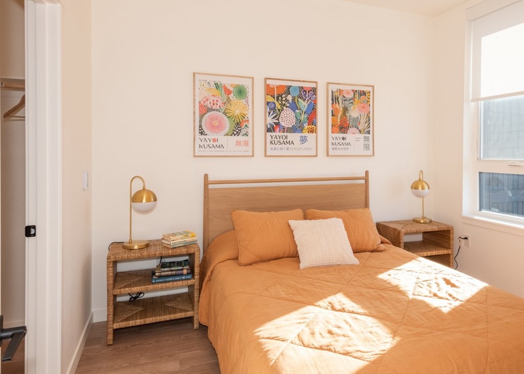 Arts Plaza Gresham Oregon Apartments A bedroom with a bed, two lamps, and a painting on the wall.