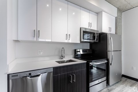 A modern kitchen with black and white cabinets and stainless steel appliances.