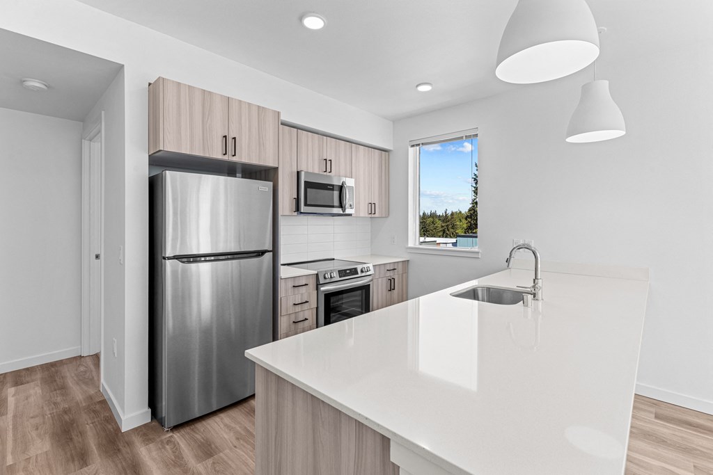 a white kitchen with stainless steel appliances and a white counter top