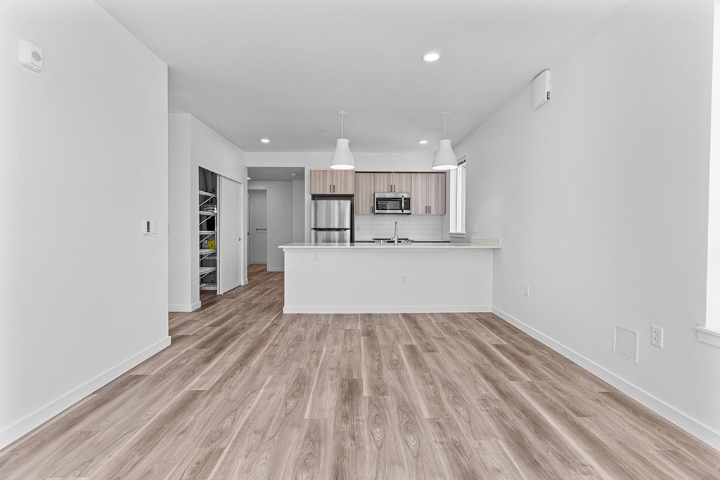 the living room and kitchen in a new home with white walls and wood flooring