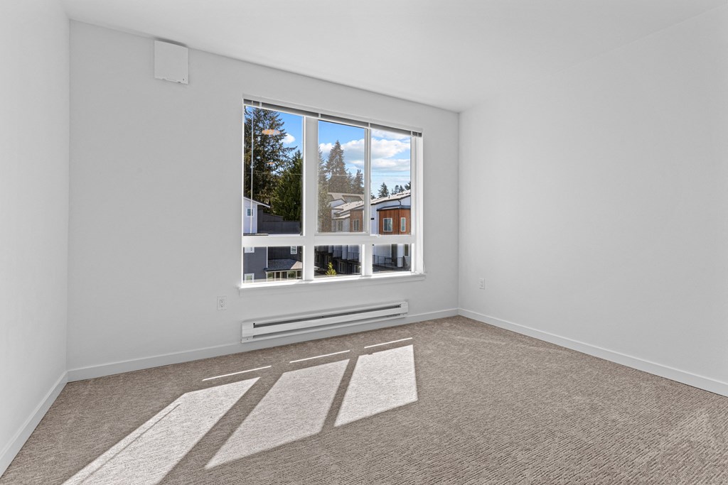 an empty room with a large window and carpeting