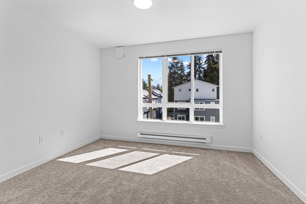 an empty living room with a large window and carpeting