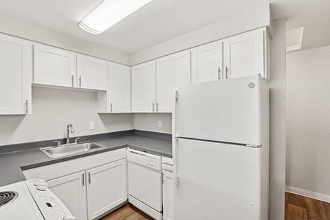 A white refrigerator is in a kitchen with white cabinets.