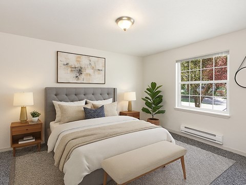 A bedroom with a large bed and a window showing a view of trees.
