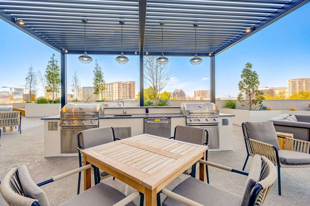 a patio with a table and chairs and barbecue grills