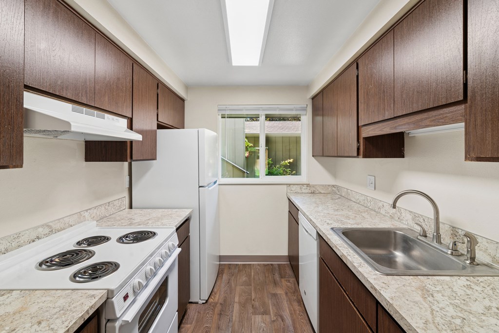 A kitchen with white appliances and brown cabinets.