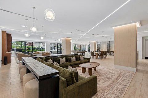 A modern living room with a long table and green couches.