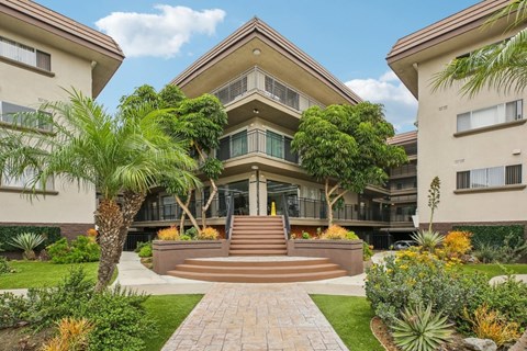 A large house with a front yard and a staircase leading to the entrance.