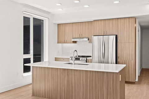 A modern kitchen with a white countertop and wooden cabinets.