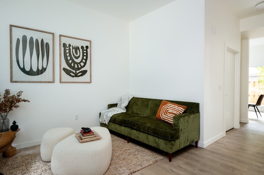 The Wes Gresham Oregon Apartments A living room with a green couch and two white ottomans.