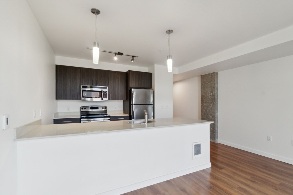 A modern kitchen with a white countertop and stainless steel appliances.