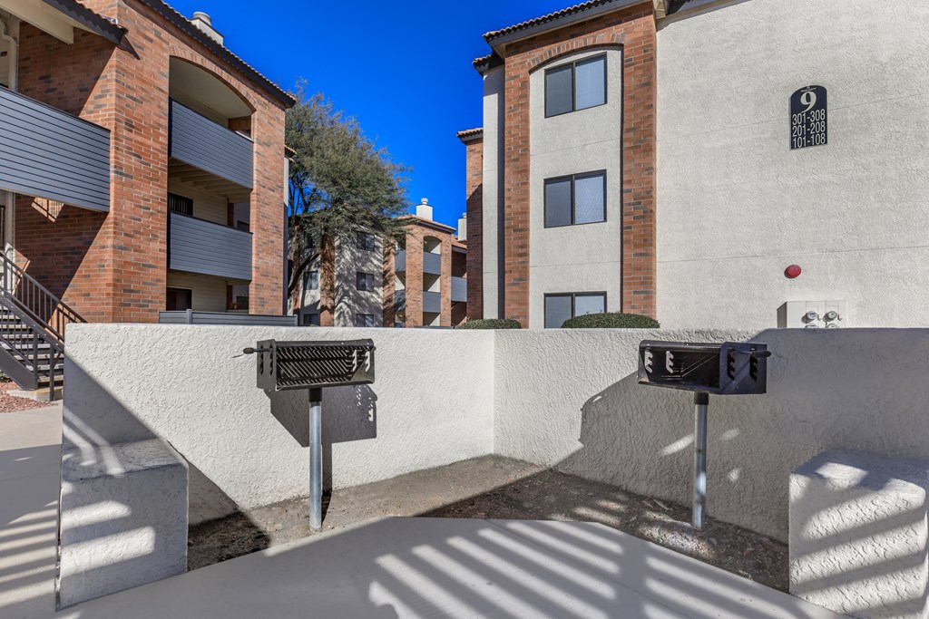 A parking meter is in front of a building with a tree in the background.
