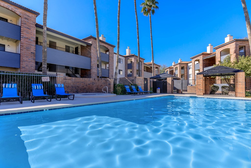 A swimming pool surrounded by palm trees and apartment buildings.