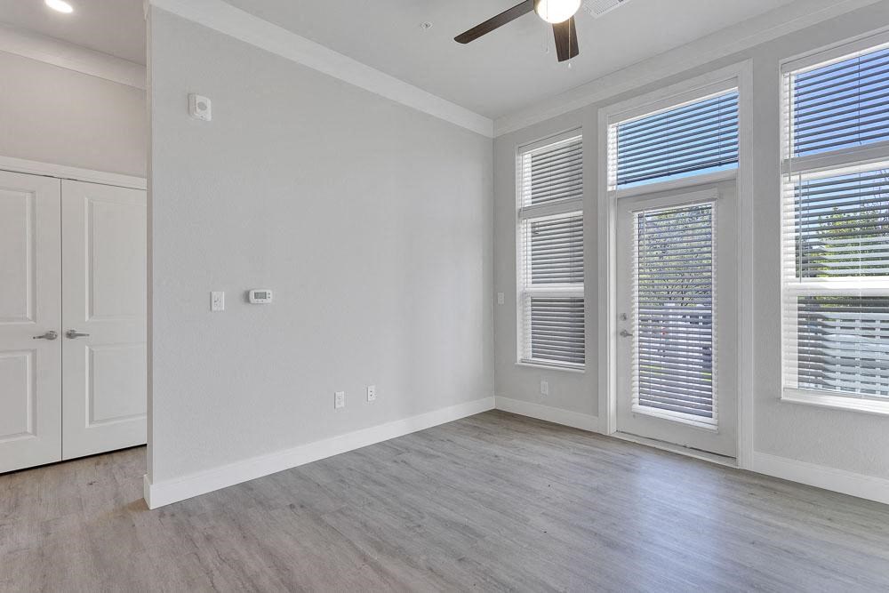 an empty living room with windows and a ceiling fan