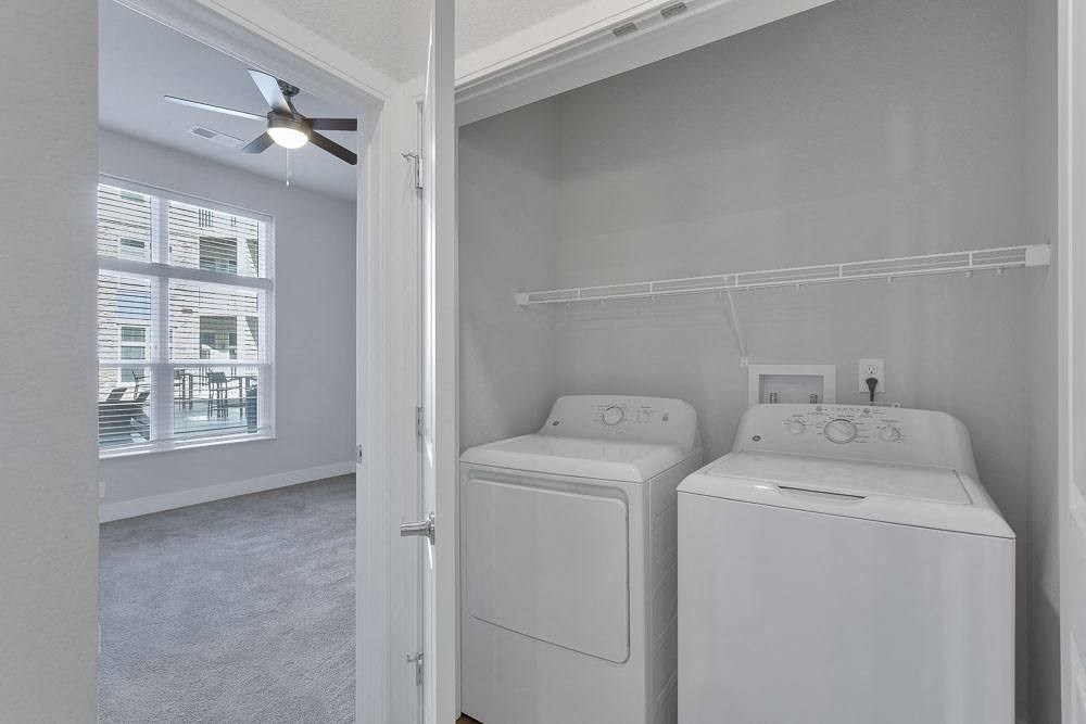 a white laundry room with two washes and a dryer