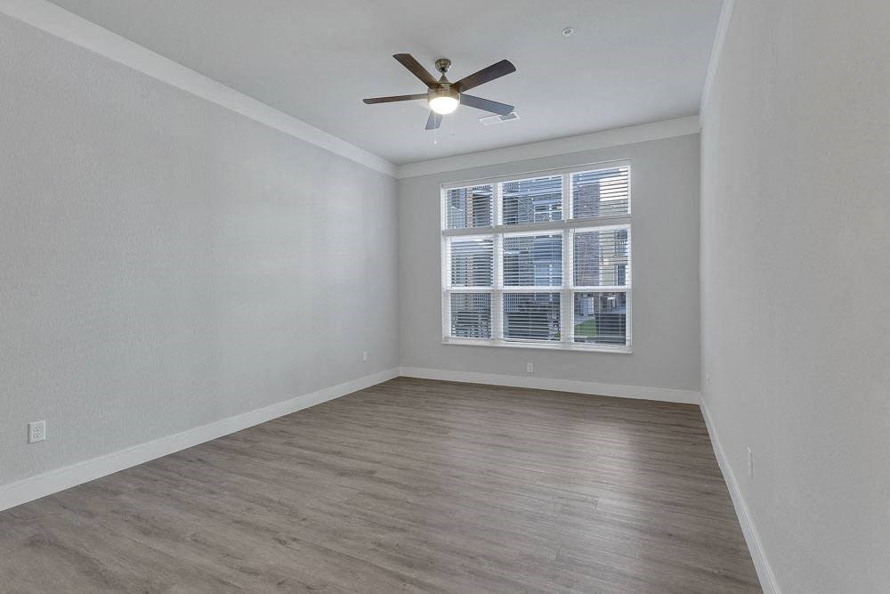 an empty living room with a ceiling fan and a window