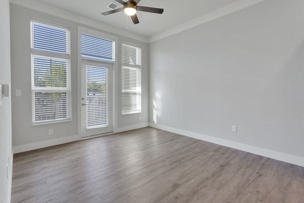 an empty living room with wood floors and a ceiling fan