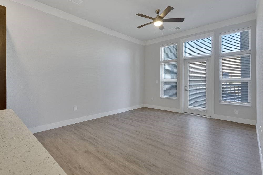 an empty living room with a ceiling fan and a window