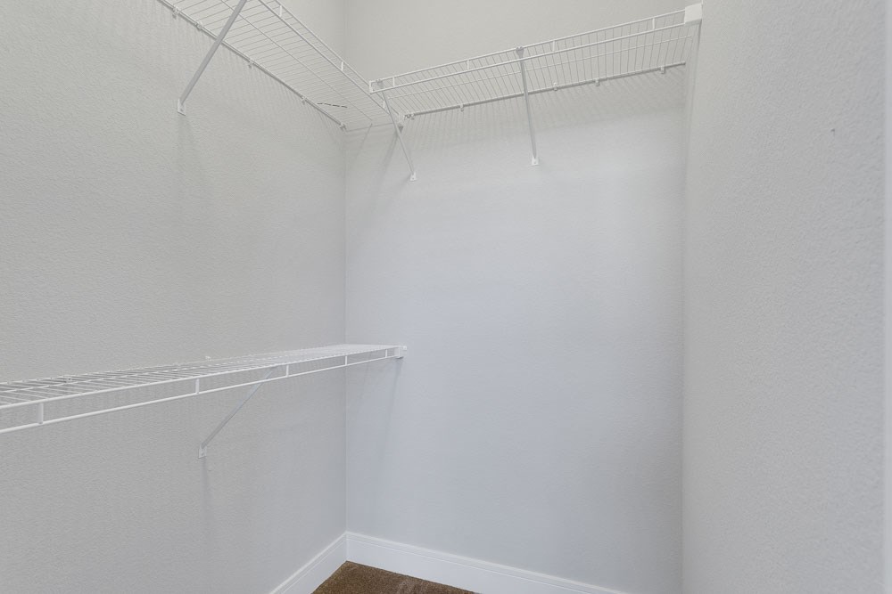 a walk in closet with a white wall and a hanging rack on the wall