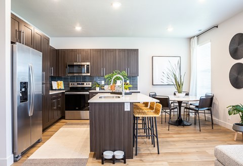 A modern kitchen with a refrigerator, sink, and dining table.