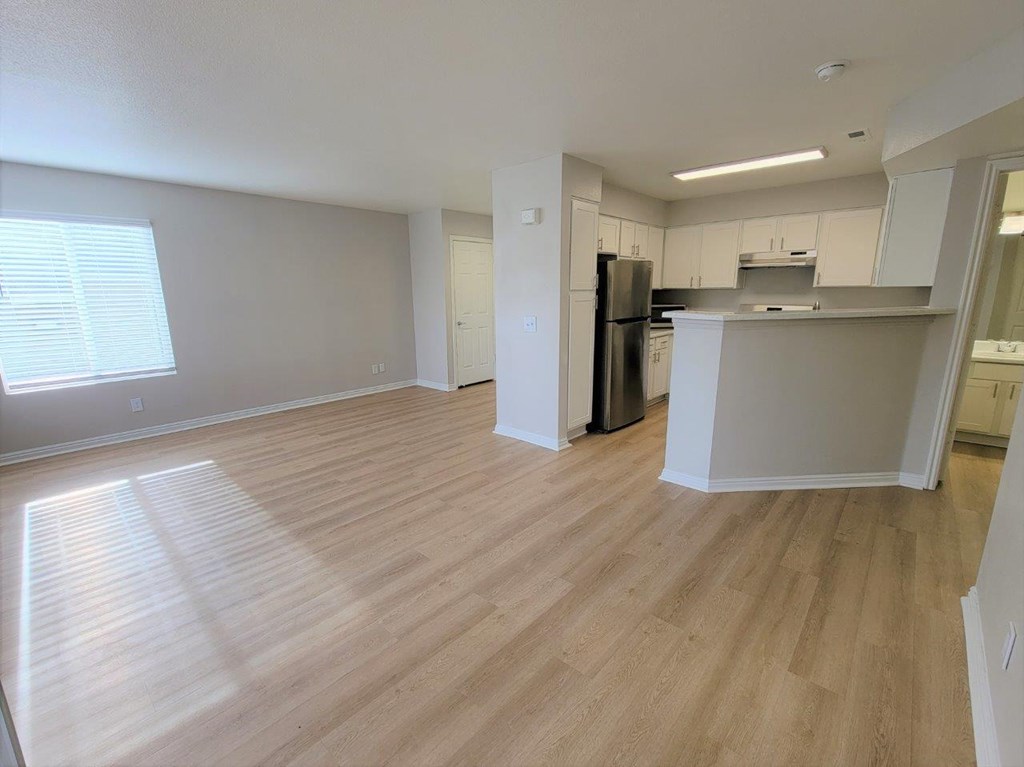 an empty living room and kitchen with wood flooring