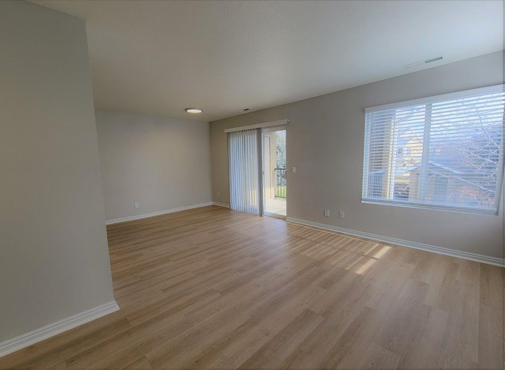 an empty living room with wood floors and a window