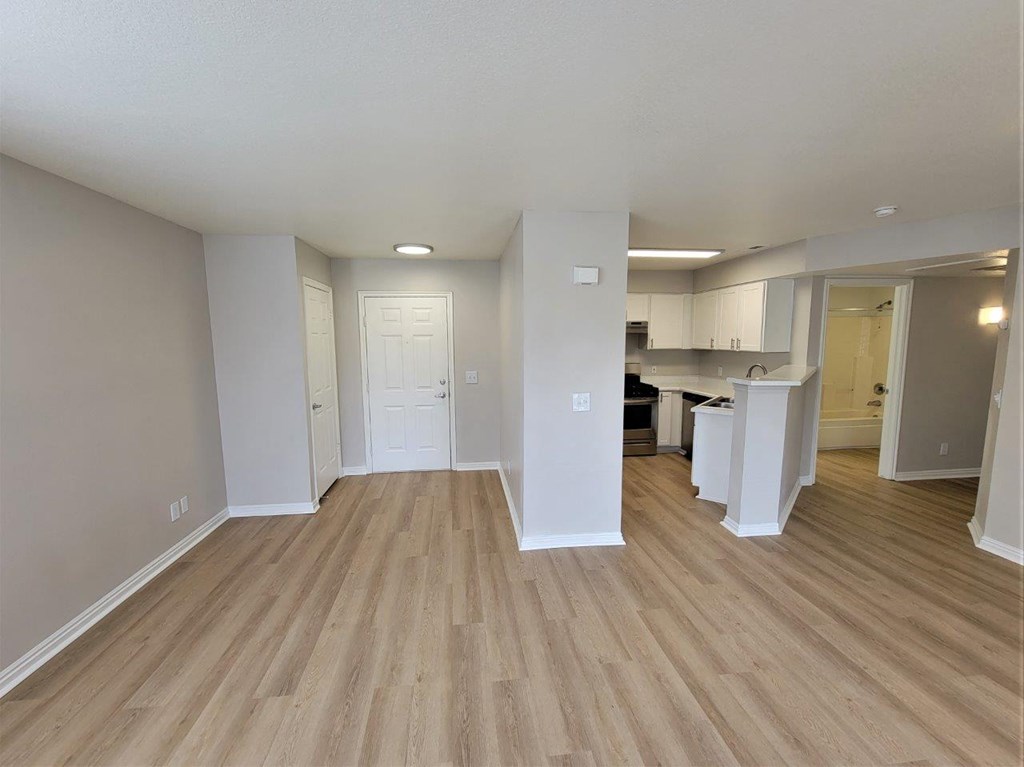 an empty living room and kitchen with wood flooring