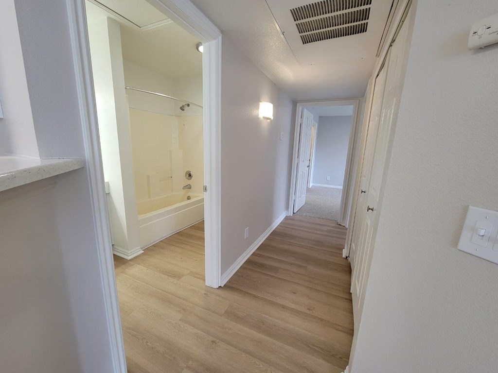 a renovated hallway with wood flooring and white walls