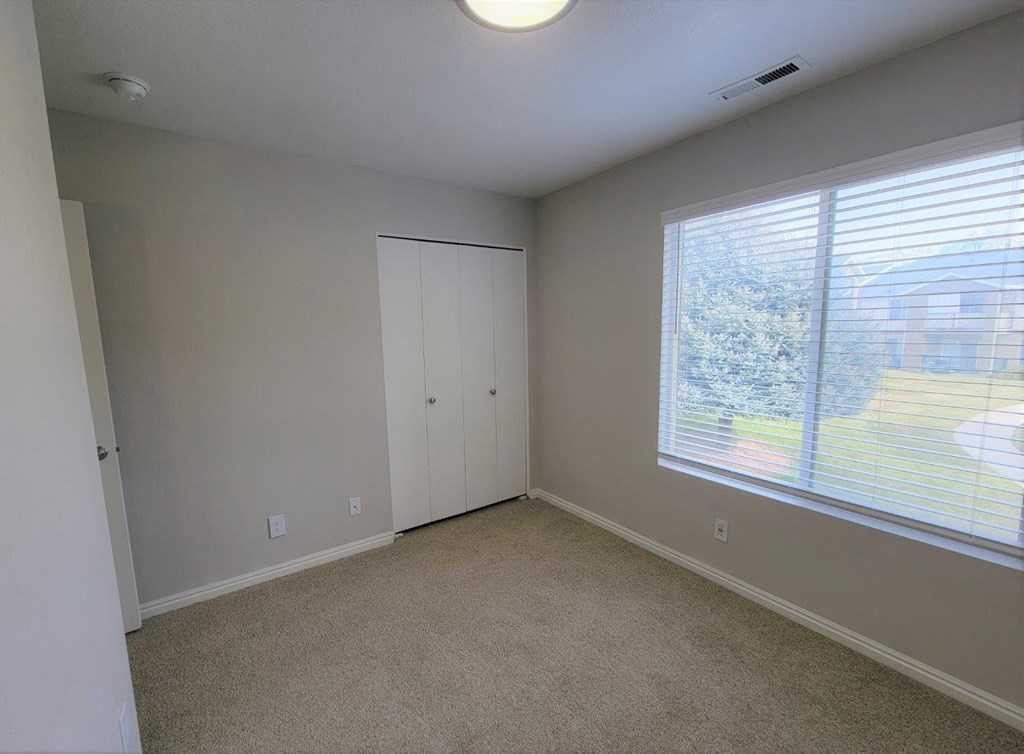 a bedroom with a large window and a closet