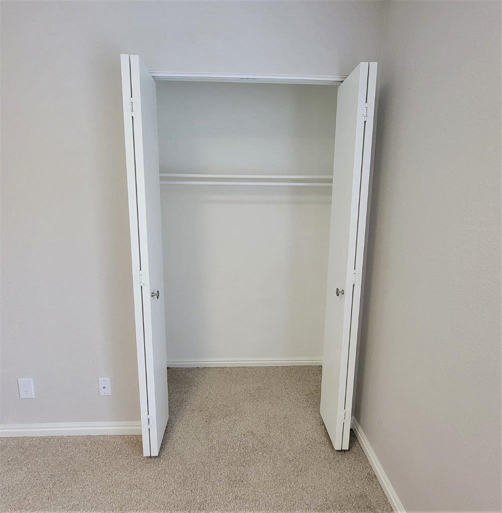 an open closet in an empty room with carpet