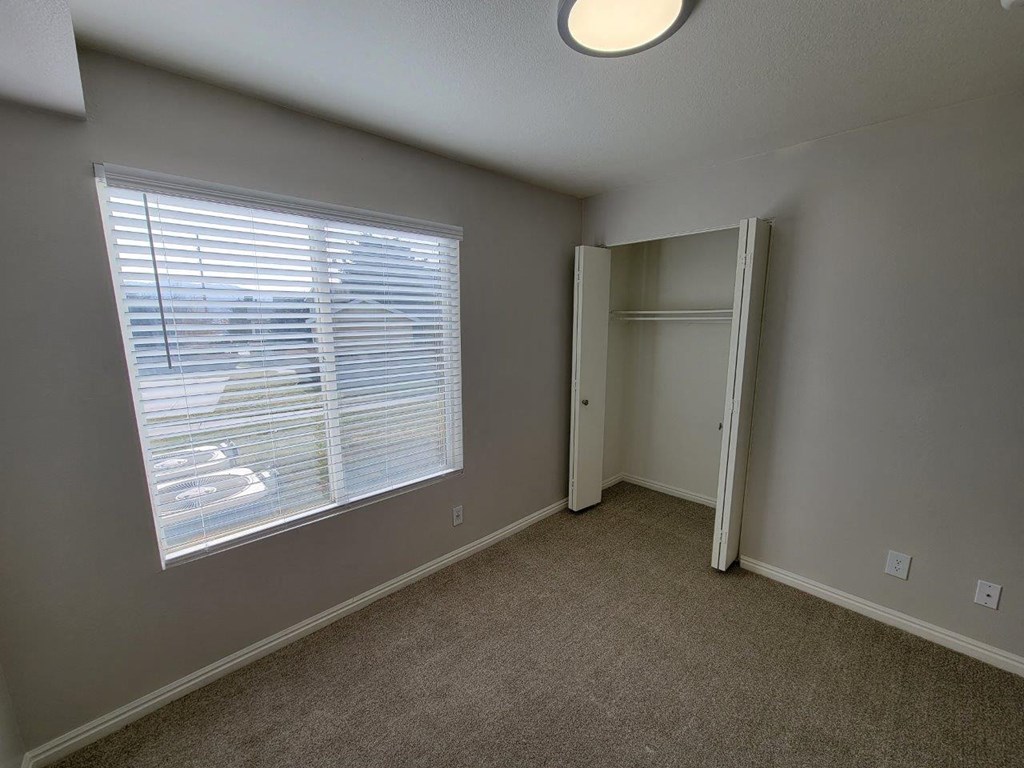 a bedroom with a large window and a closet