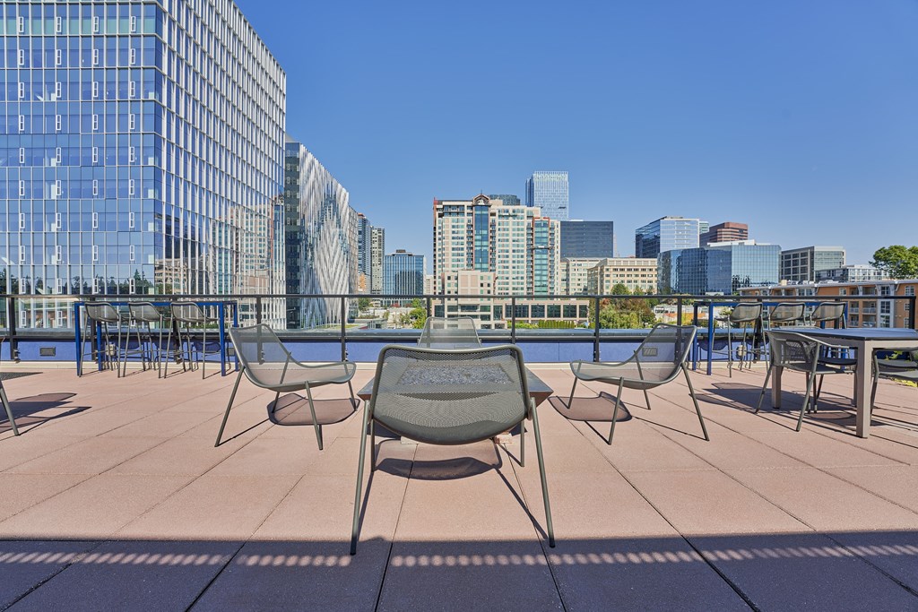 a rooftop patio with tables and chairs and a view of the city