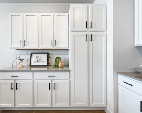A kitchen with white cabinets and a framed picture on the counter.