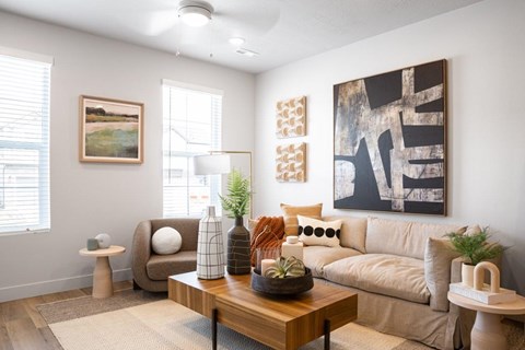 A living room with a brown couch, a wooden coffee table, and a large abstract painting on the wall.