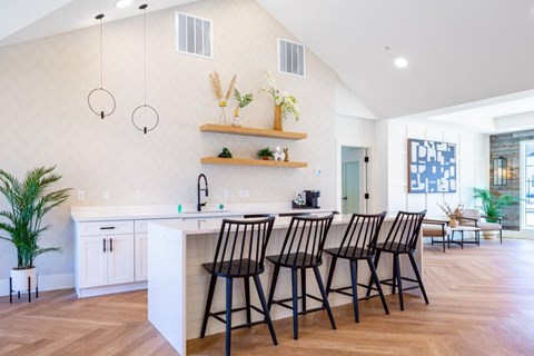 A kitchen with a white counter and black chairs.