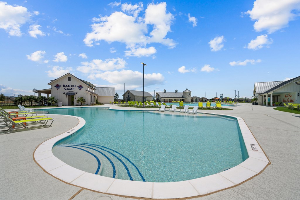 a large swimming pool with lounge chairs in front of a building