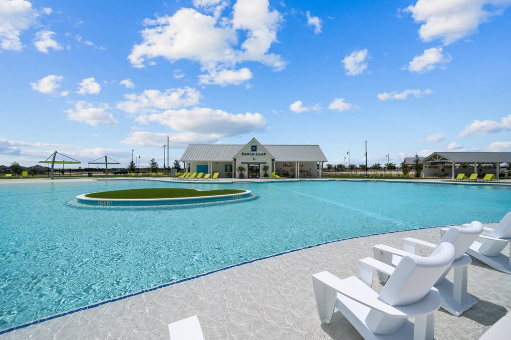 a large pool with white chairs and a building in the background