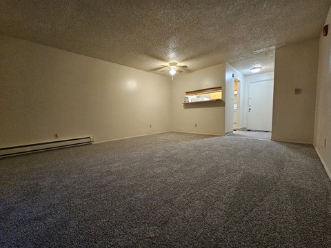 an empty living room with carpet and a ceiling fan