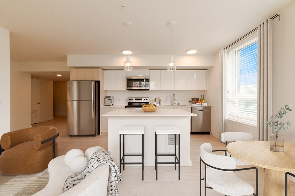 an open kitchen and living room with a white island and stainless steel appliances