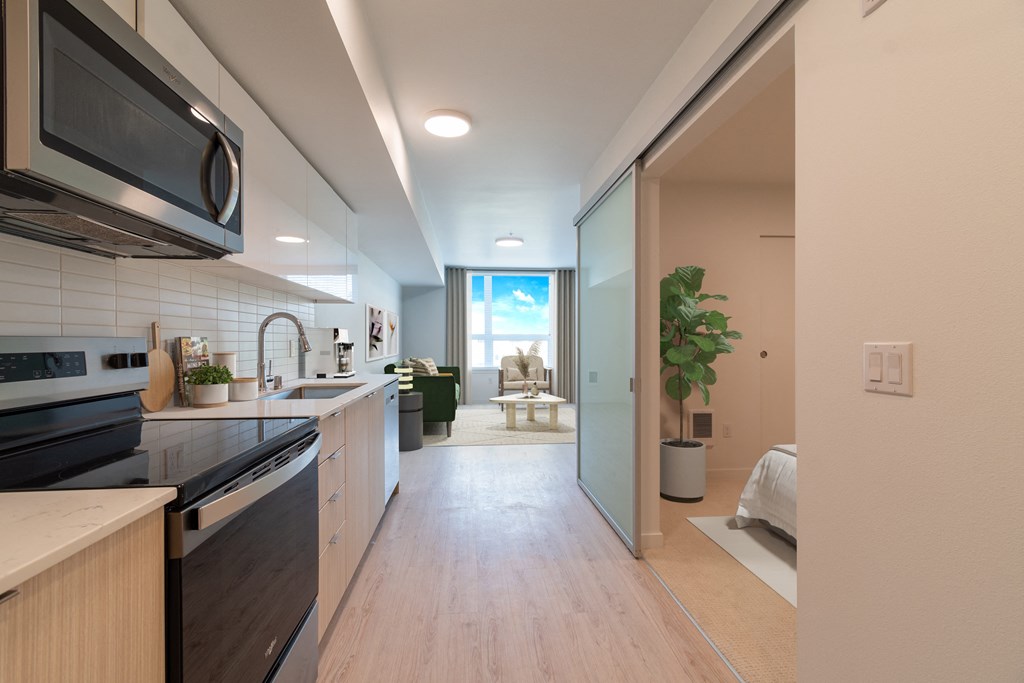 an open kitchen and living room with a view of a bedroom and a balcony