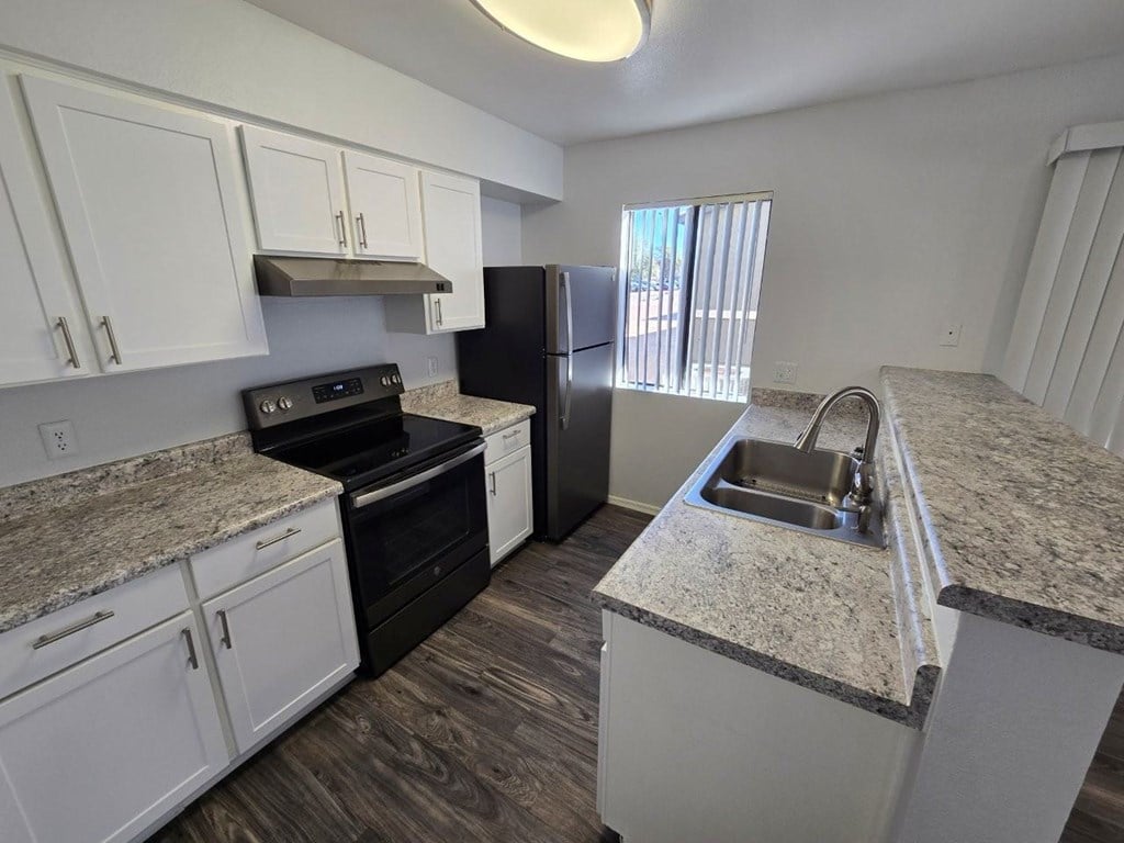A kitchen with white cabinets and granite countertops.