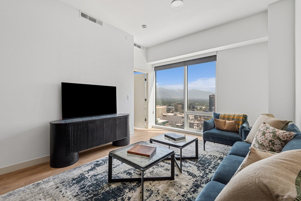 A living room with a flat screen TV and a view of the city.
