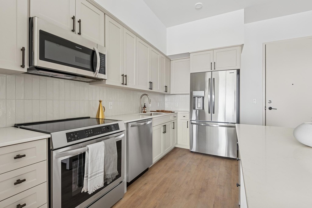 A modern kitchen with stainless steel appliances and wooden floors.