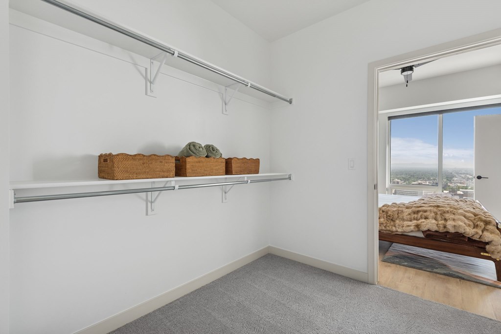 A room with a grey carpet and a window overlooking a cityscape.