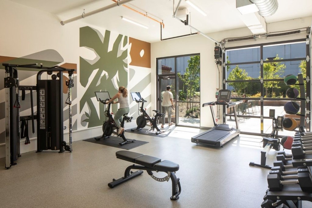 Arts Plaza Gresham Oregon Apartments fully equipped fitness center with a woman working out on a treadmill.