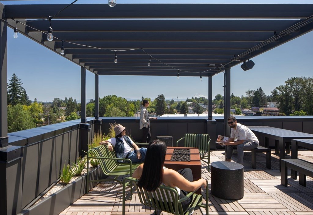 Arts Plaza Gresham Oregon Apartments A woman is sitting at a table on a patio with a man standing behind her.