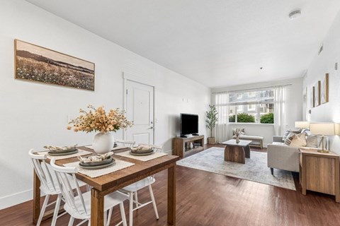 A dining room with a wooden table and white chairs.