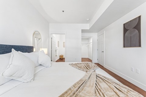 A bedroom with a large bed and a painting on the wall.